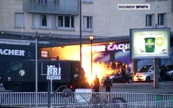 An explosion lights the front of a kosher supermarket as French police special forces launch their assault, where several people were taken hostage in eastern Paris